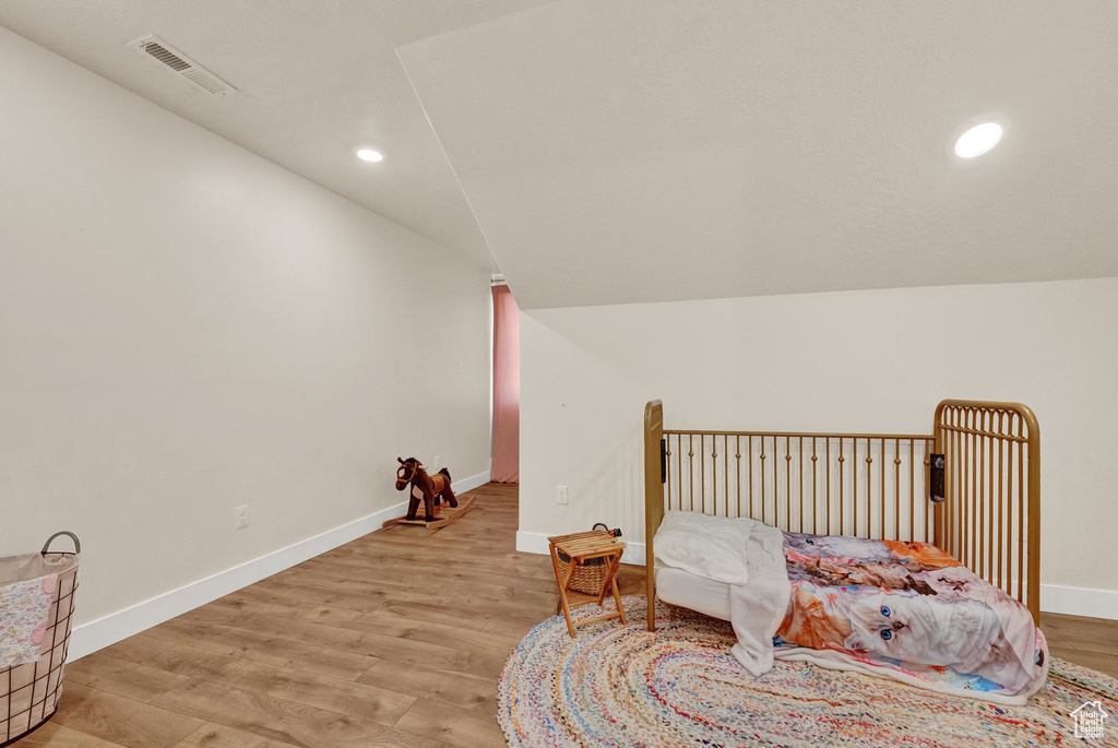 Bedroom with vaulted ceiling and light wood-type flooring