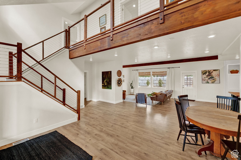 Dining area with light wood-type flooring and a towering ceiling