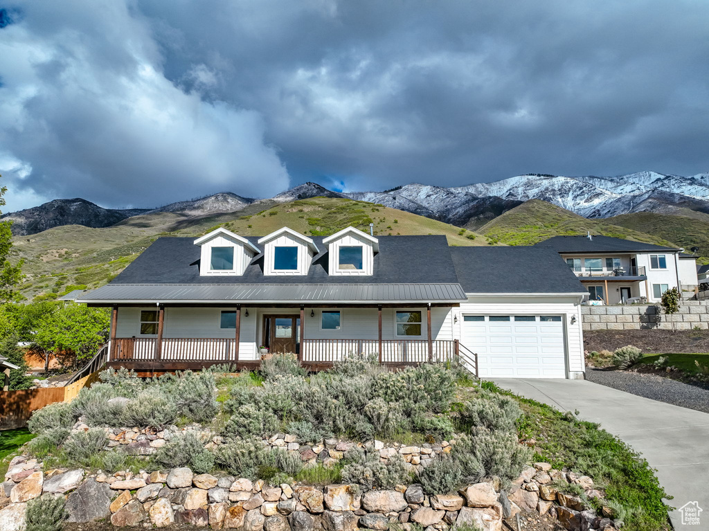 View of front of home featuring a mountain view, covered porch, and a garage