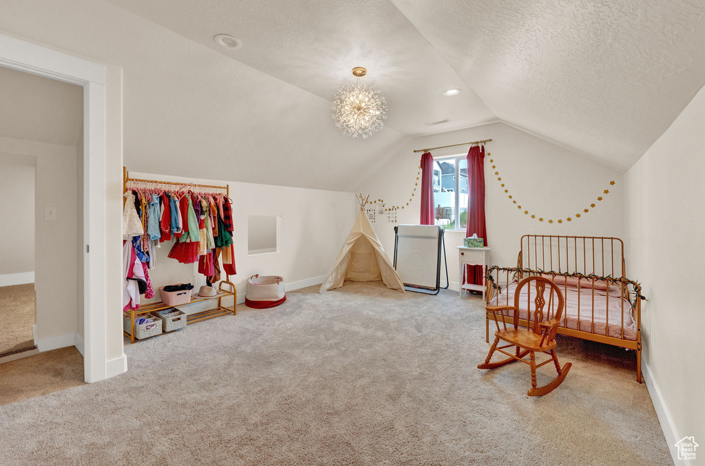 Bedroom featuring lofted ceiling, carpet flooring, an inviting chandelier, and a textured ceiling