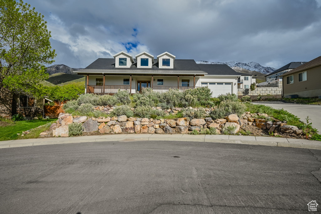 View of front of home with a mountain view, a porch, and a garage