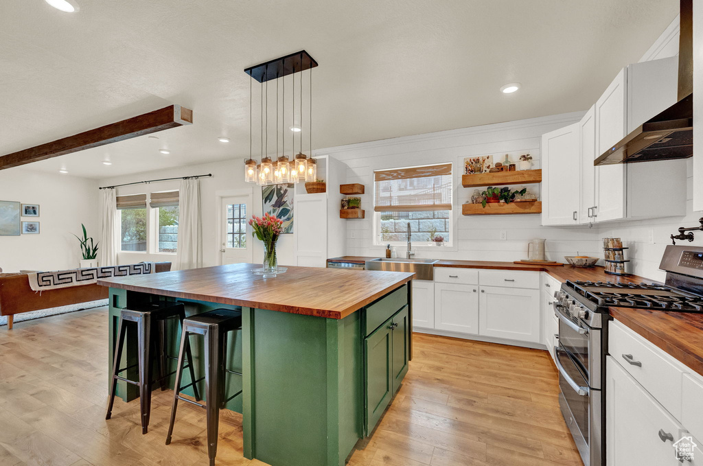 Kitchen featuring white cabinets, wooden counters, double oven range, and a kitchen island