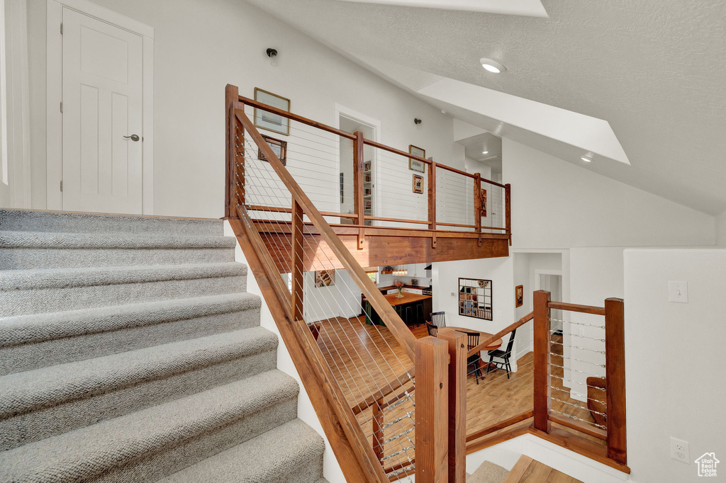 Stairway with hardwood / wood-style flooring and a skylight