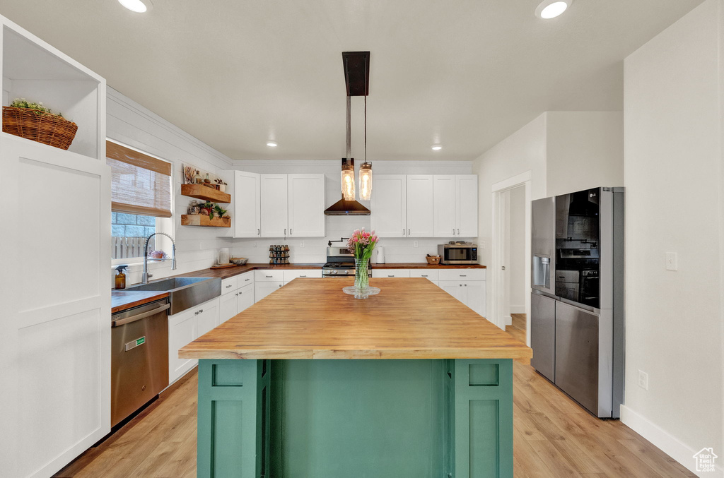 Kitchen with green cabinetry, stainless steel appliances, butcher block countertops, and sink