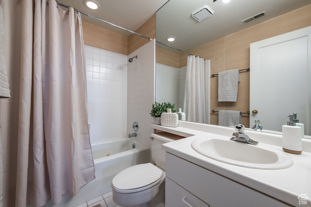 Full bathroom featuring shower / bathtub combination with curtain, tile floors, toilet, and vanity with extensive cabinet space