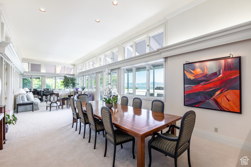 Carpeted dining area featuring a wealth of natural light and crown molding