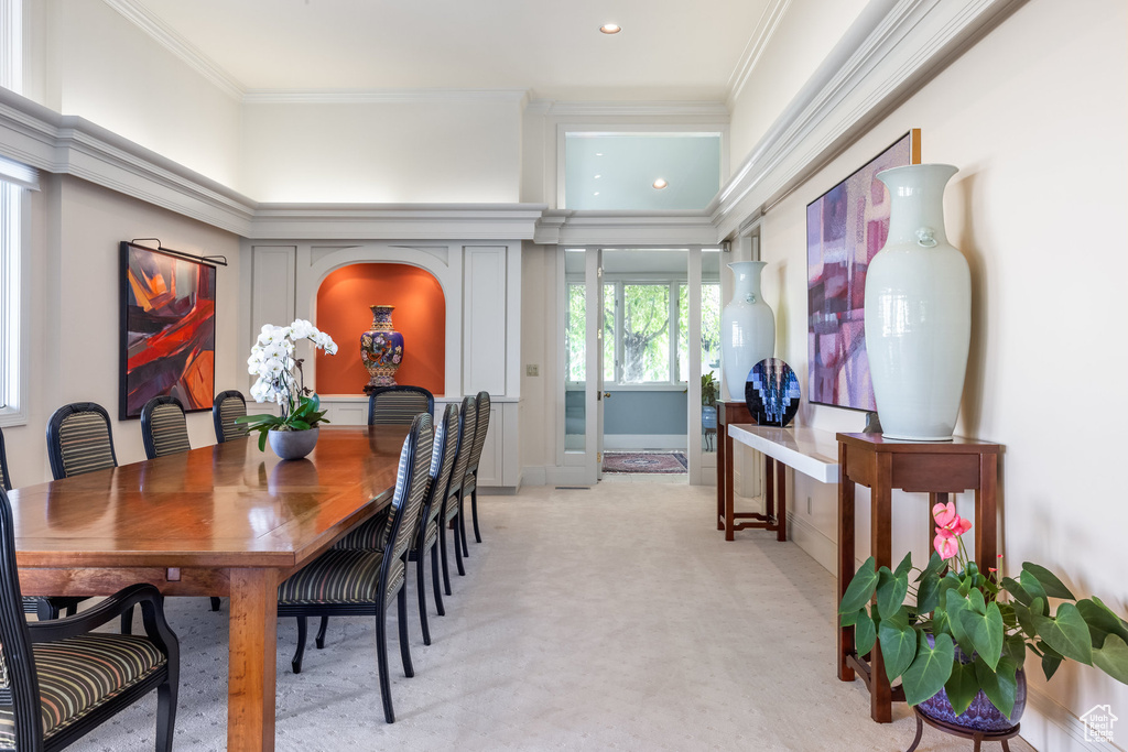 Dining area with light carpet and ornamental molding