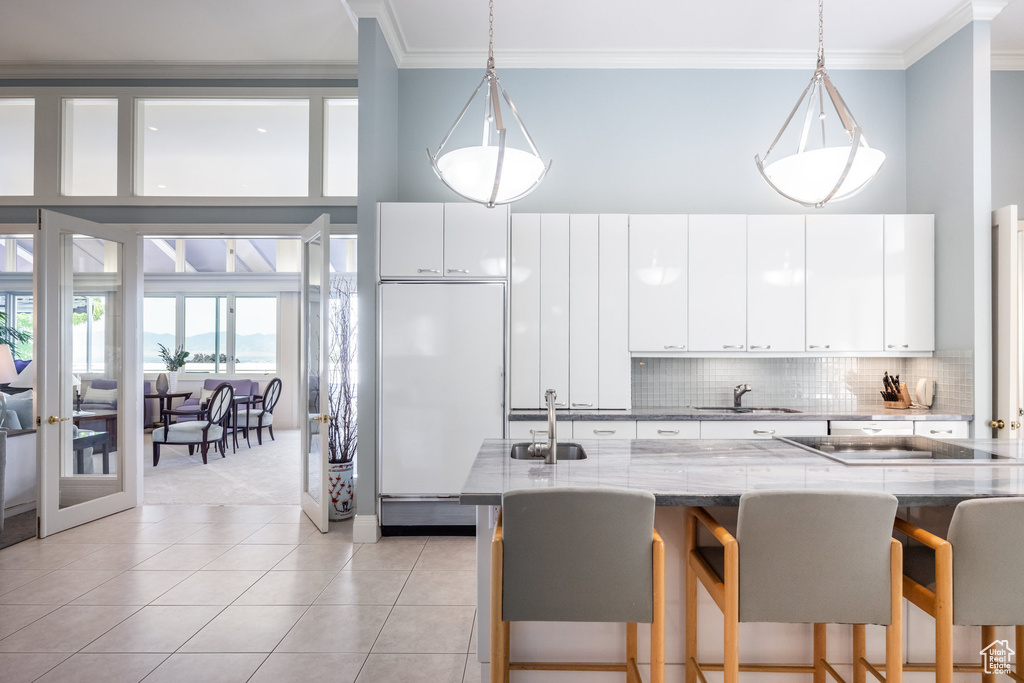 Kitchen featuring tasteful backsplash, hanging light fixtures, sink, white cabinets, and built in refrigerator