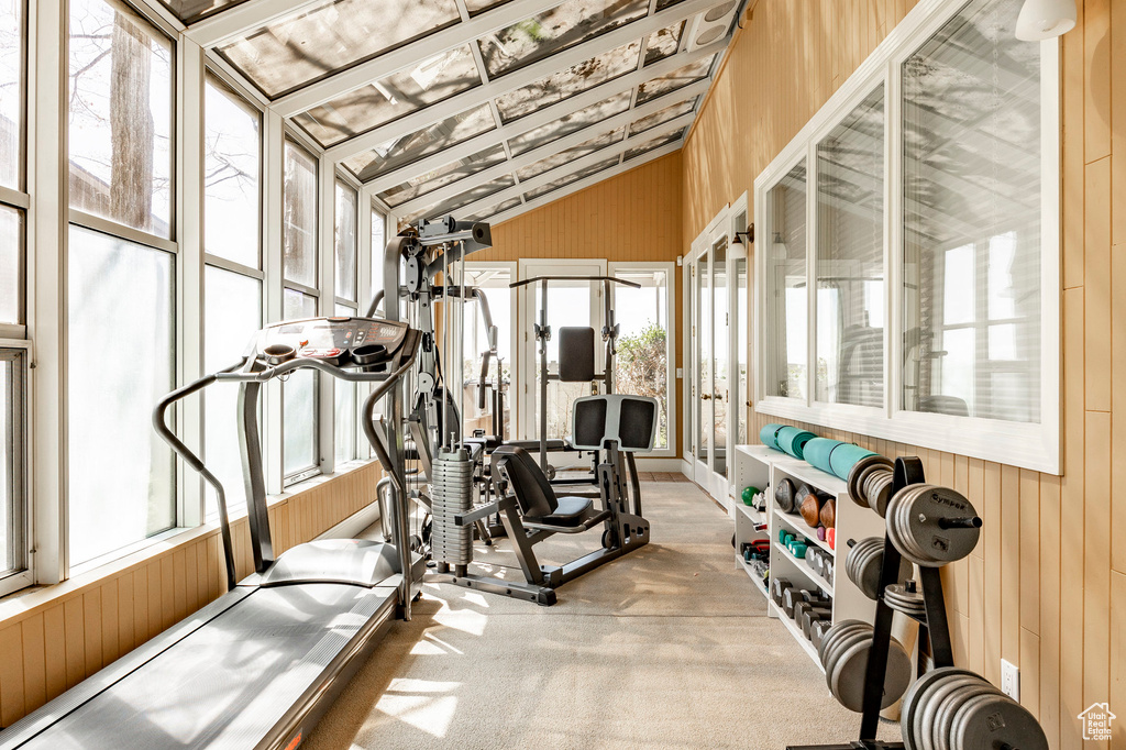 Workout room with carpet flooring, wooden walls, and lofted ceiling