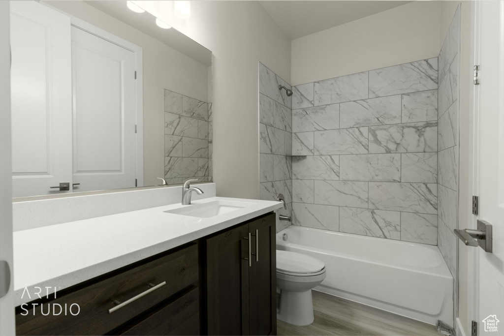 Full bathroom featuring wood-type flooring, vanity, toilet, and tiled shower / bath