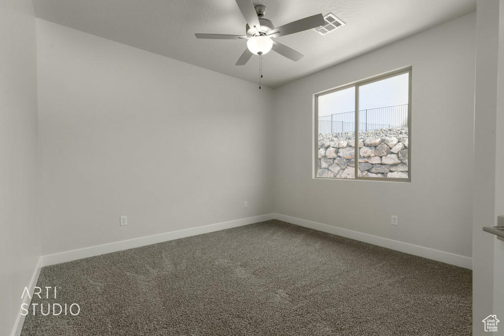 Unfurnished room featuring ceiling fan and dark carpet