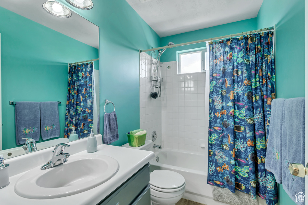 Full bathroom featuring toilet, large vanity, and shower / tub combo with curtain