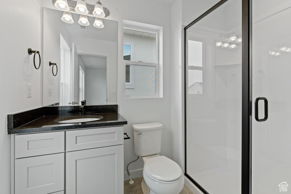 Bathroom featuring walk in shower, toilet, large vanity, and a notable chandelier