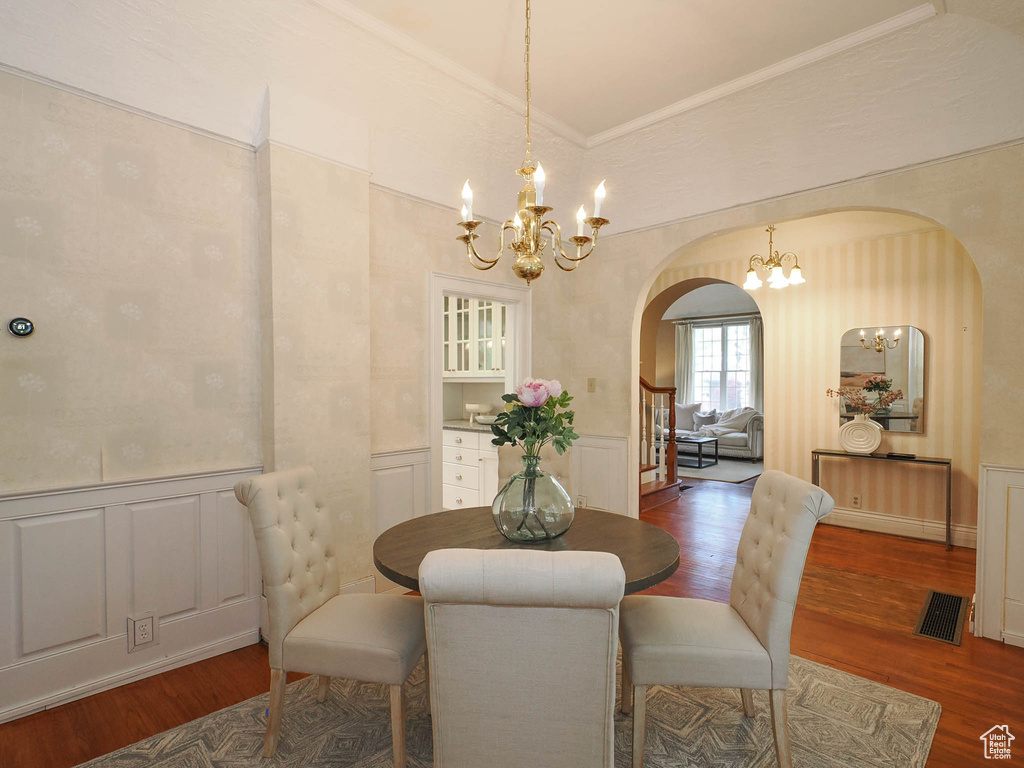 Dining space with an inviting chandelier, hardwood / wood-style flooring, and ornamental molding