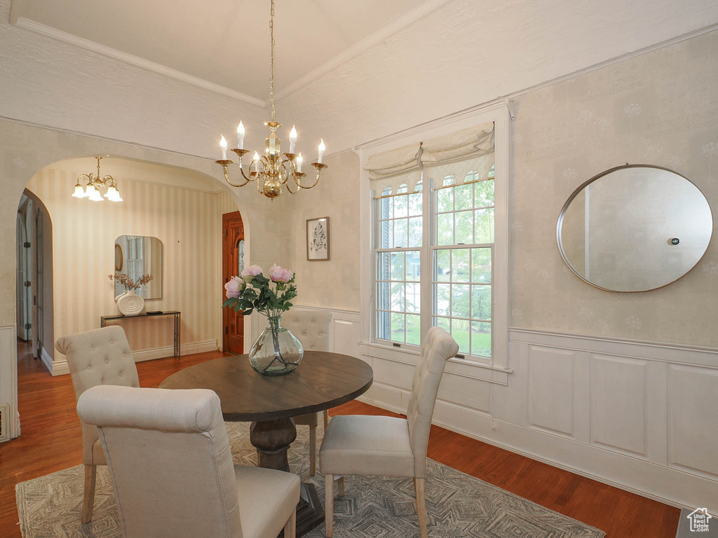 Dining area featuring hardwood / wood-style floors, crown molding, and a chandelier