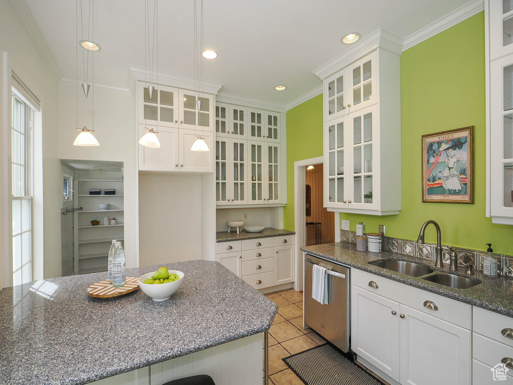 Kitchen with white cabinets, sink, light tile flooring, stainless steel dishwasher, and hanging light fixtures