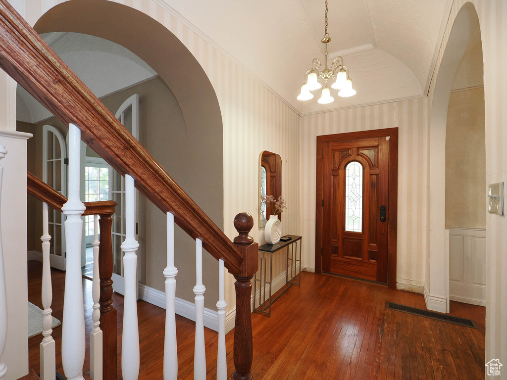 Foyer with hardwood / wood-style floors, vaulted ceiling, and an inviting chandelier