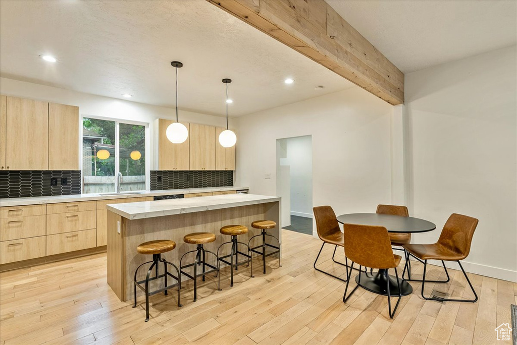 Kitchen featuring a kitchen island, light hardwood / wood-style floors, hanging light fixtures, and beamed ceiling