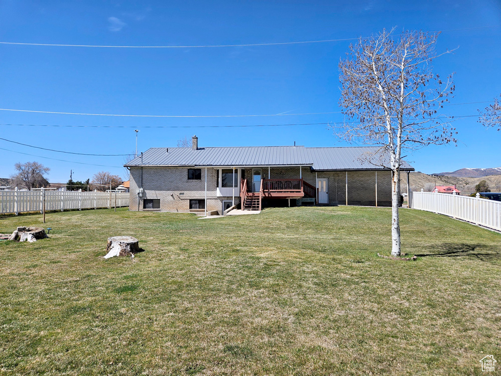 Back of house featuring a yard and a wooden deck