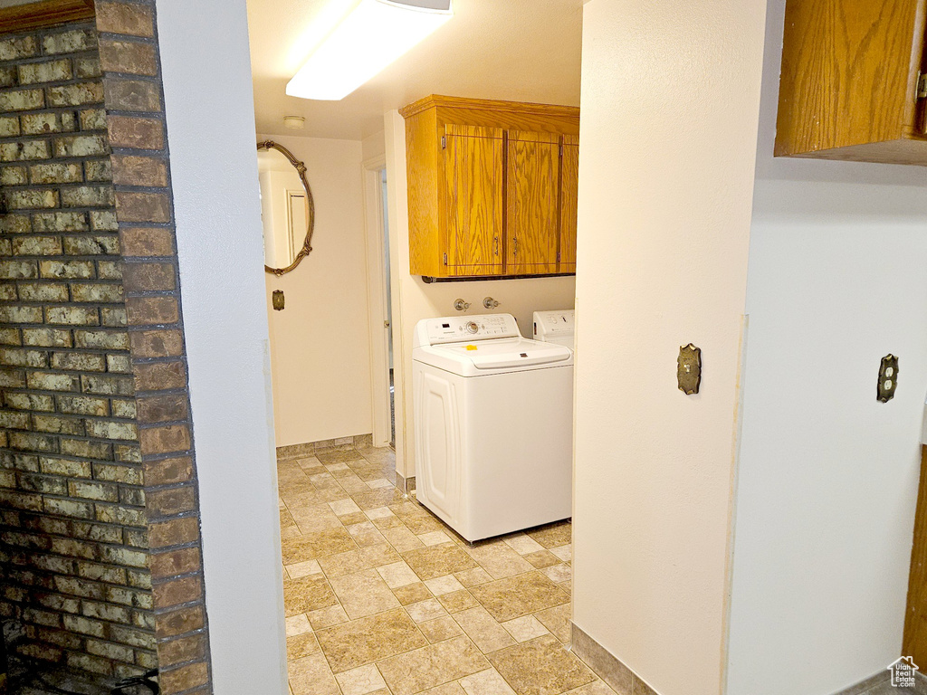 Laundry area featuring cabinets, washing machine and dryer, and light tile flooring