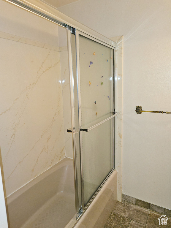 Bathroom with bath / shower combo with glass door and tile floors