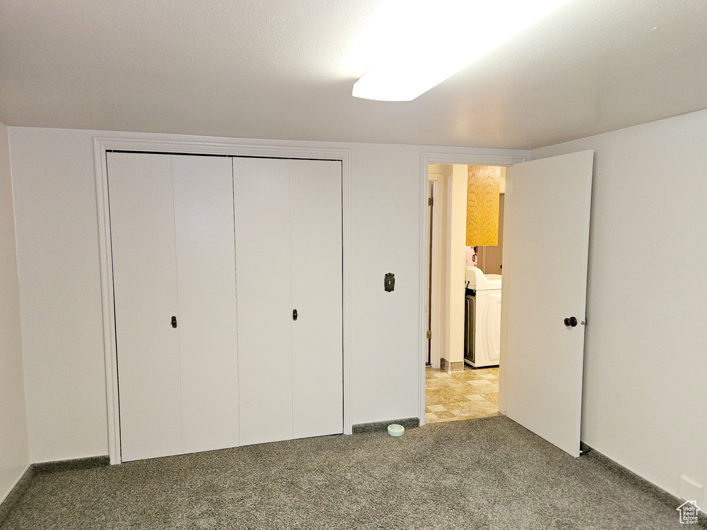 Unfurnished bedroom with light colored carpet, separate washer and dryer, and a closet