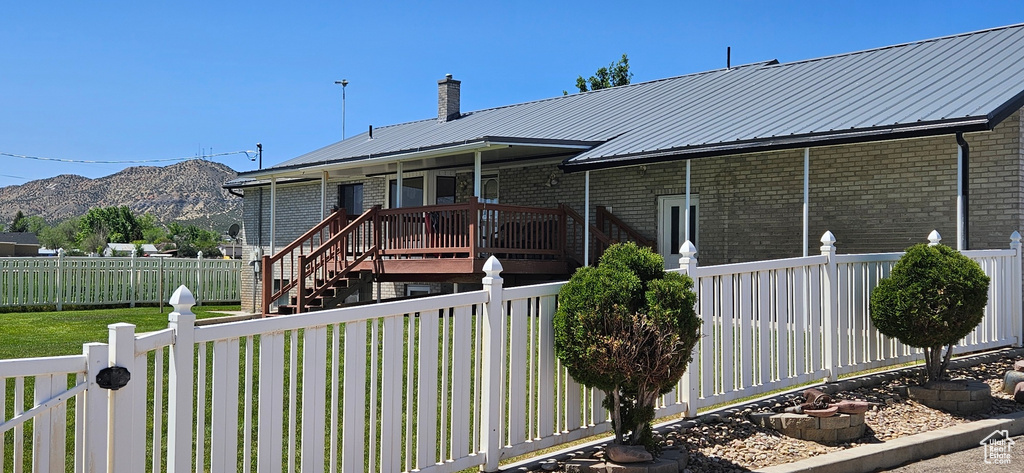 View of front of home with a fenced backyard, brick siding, a mountain view, and metal roof
