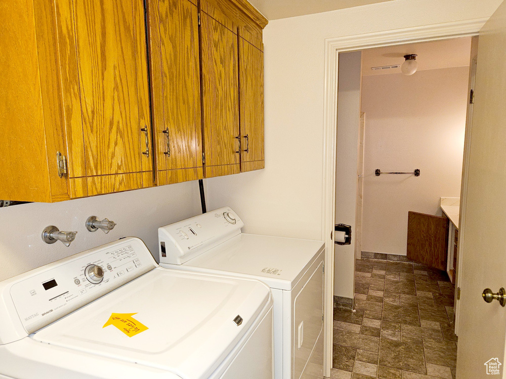 Laundry area with washer hookup, dark tile floors, cabinets, and washer and dryer