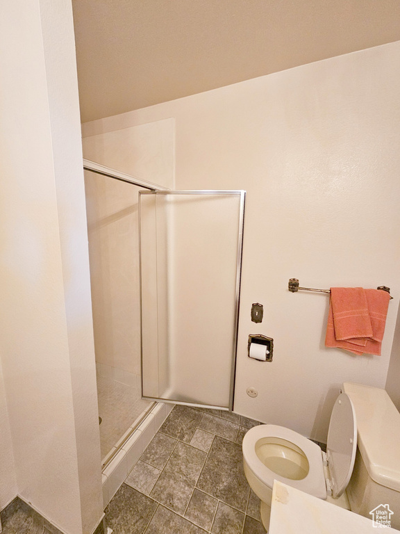 Bathroom featuring walk in shower, tile floors, and toilet