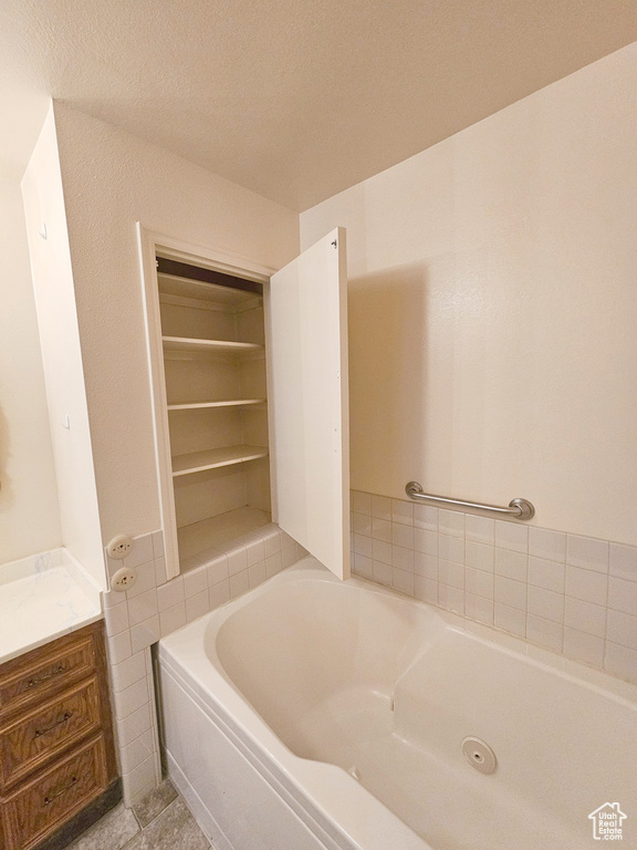 Bathroom featuring a bathtub, tile floors, vanity, and a textured ceiling