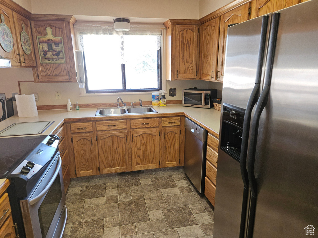 Kitchen featuring sink, appliances with stainless steel finishes, and dark tile flooring