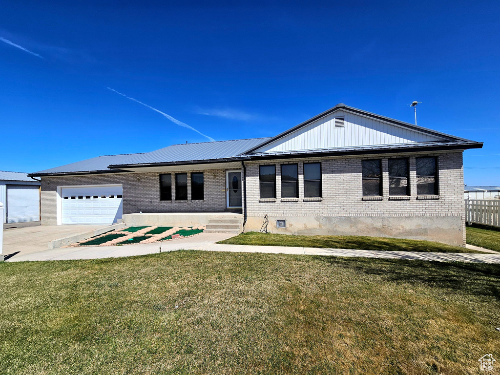 Ranch-style house featuring a front yard and a garage