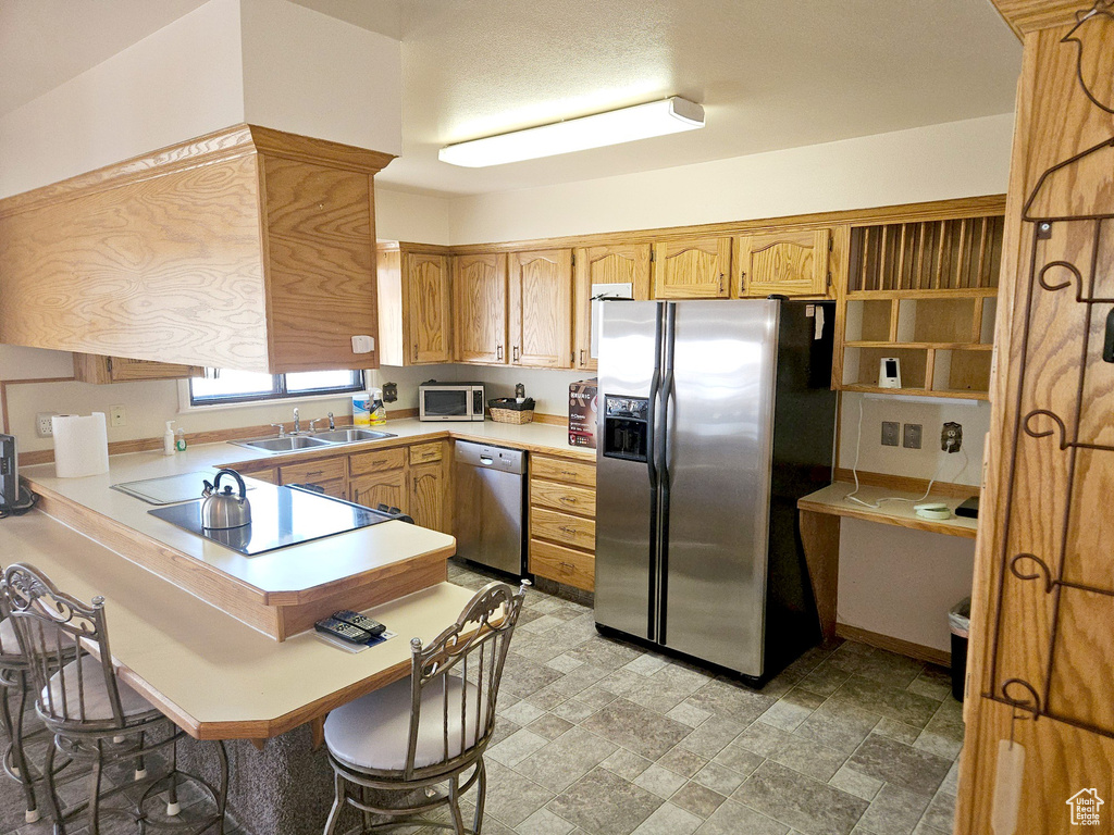 Kitchen with kitchen peninsula, stainless steel appliances, a kitchen breakfast bar, sink, and light tile floors