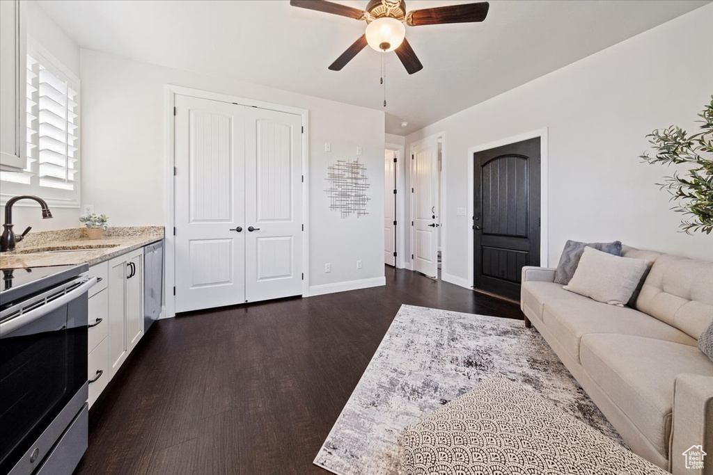 Living room featuring dark hardwood / wood-style flooring, ceiling fan, and sink