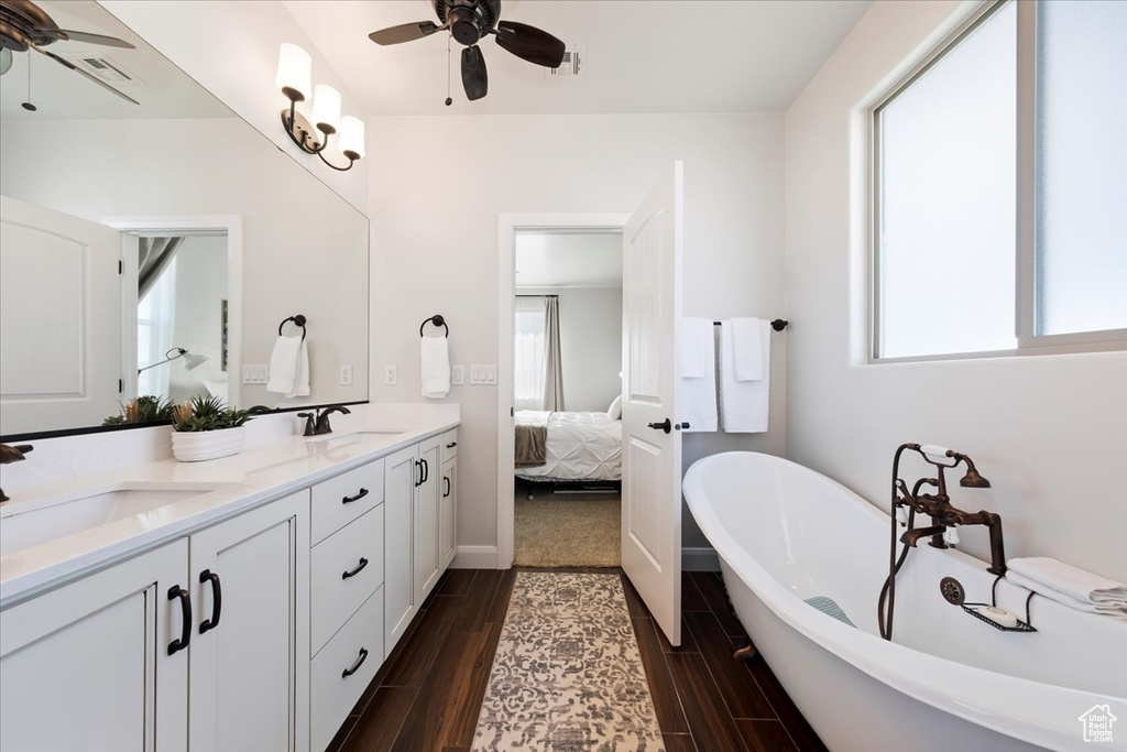 Bathroom featuring plenty of natural light, ceiling fan, vanity with extensive cabinet space, and double sink