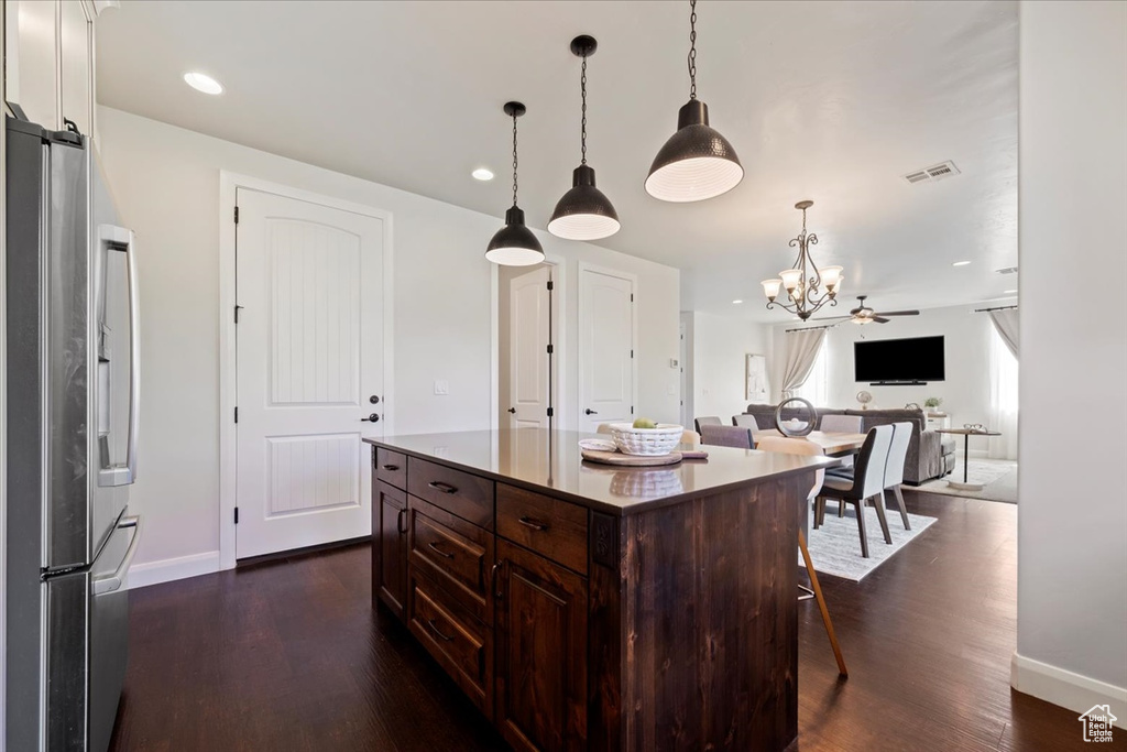 Kitchen featuring pendant lighting, a breakfast bar, stainless steel refrigerator with ice dispenser, dark hardwood / wood-style floors, and dark brown cabinets