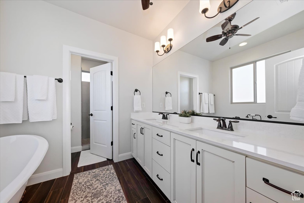Bathroom featuring ceiling fan, a bath, and double sink vanity