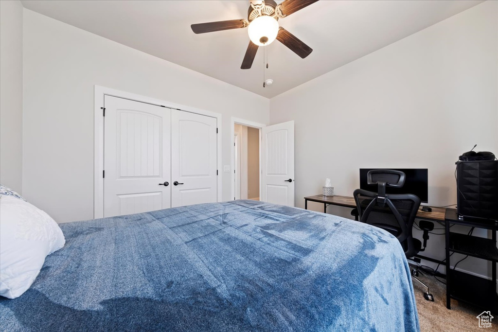 Bedroom with a closet, ceiling fan, and carpet flooring