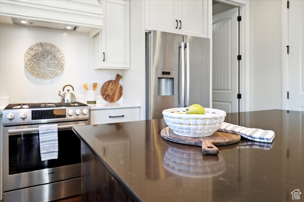 Kitchen featuring appliances with stainless steel finishes, dark stone countertops, and white cabinetry