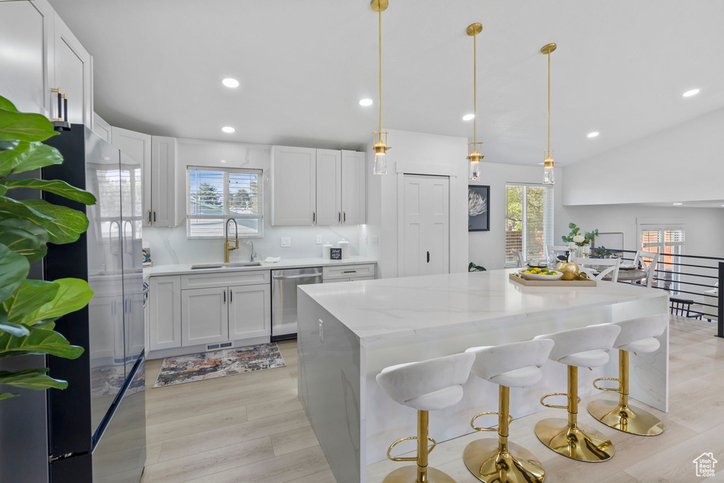 Kitchen with plenty of natural light, stainless steel appliances, light wood-type flooring, and white cabinetry