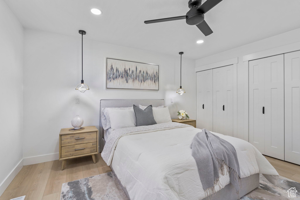 Bedroom featuring multiple closets, ceiling fan, and light wood-type flooring