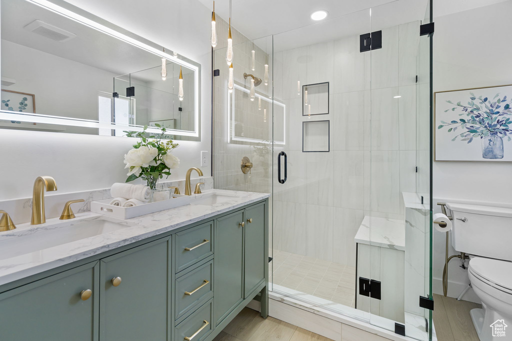 Bathroom featuring a shower with door, toilet, hardwood / wood-style floors, and double sink vanity