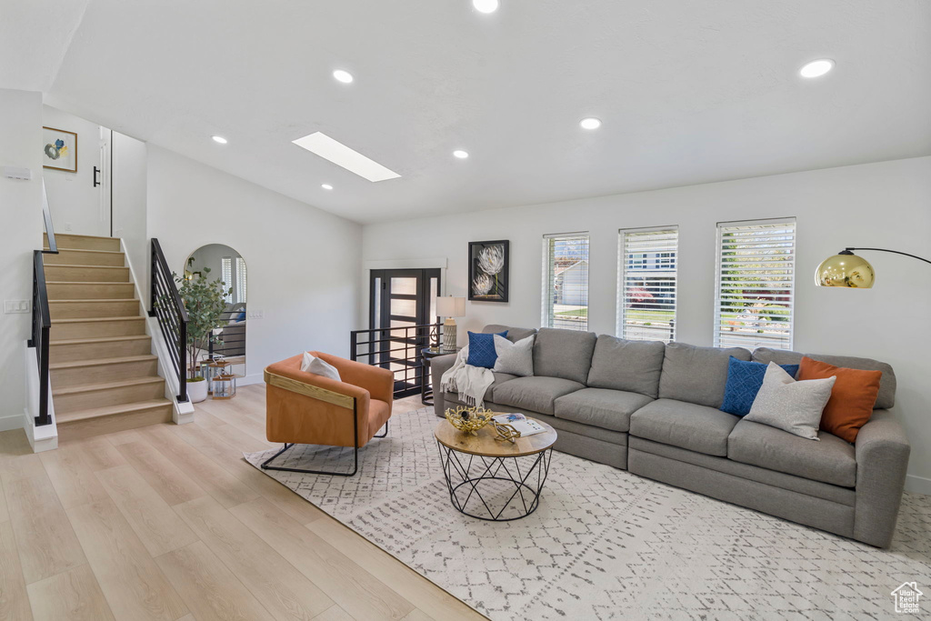Living room with a skylight and light hardwood / wood-style flooring