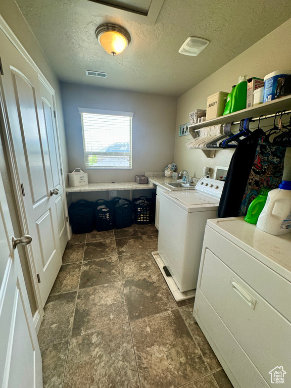 Laundry room with a textured ceiling, washer and clothes dryer, sink, dark tile flooring, and hookup for a washing machine