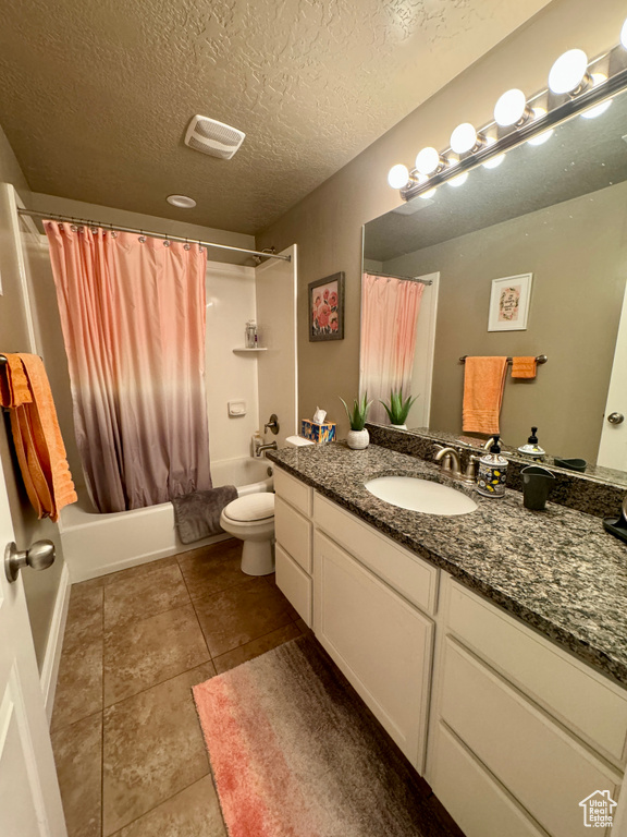 Full bathroom featuring a textured ceiling, shower / tub combo with curtain, toilet, tile floors, and vanity