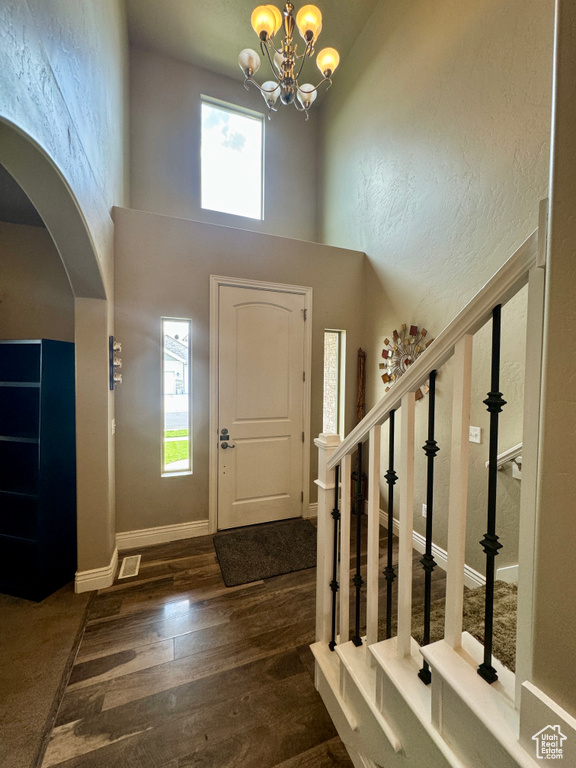 Entryway featuring a notable chandelier, a high ceiling, and dark carpet