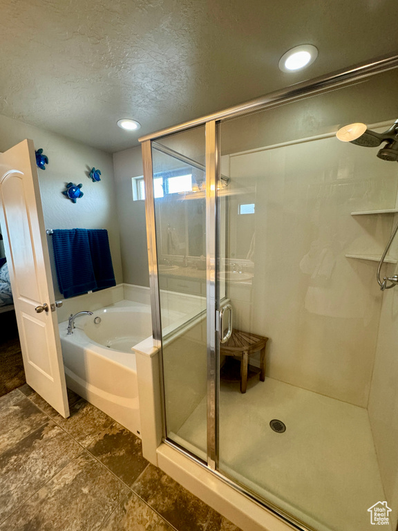Bathroom with tile floors, separate shower and tub, and a textured ceiling