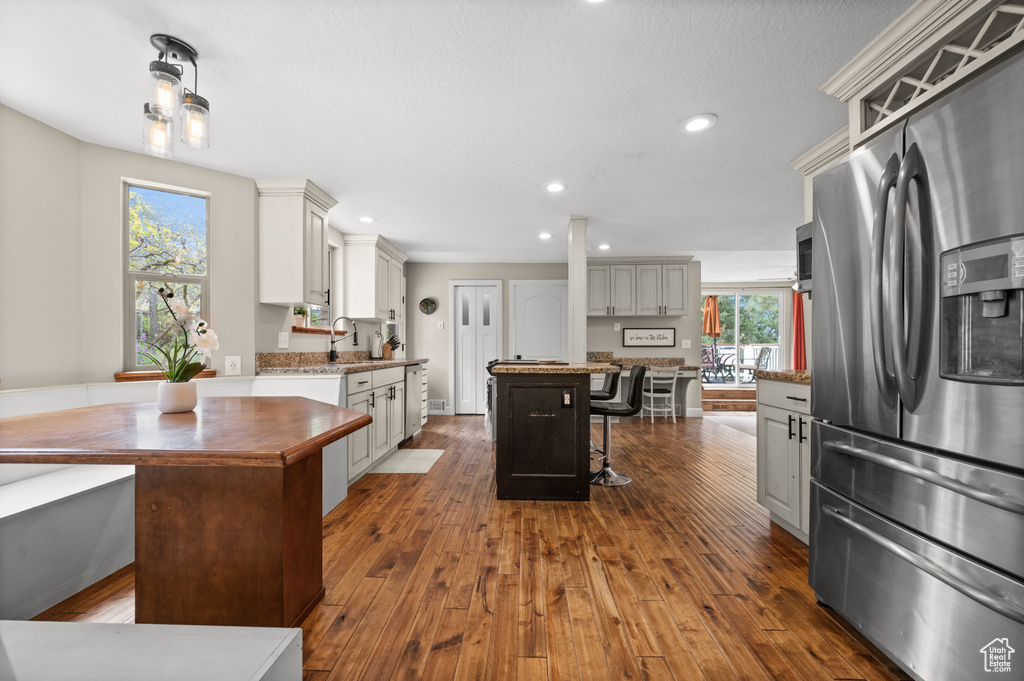 Kitchen with a kitchen island, stainless steel refrigerator with ice dispenser, and dark hardwood / wood-style floors