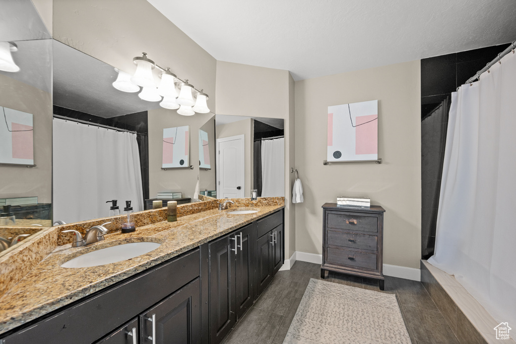 Bathroom with vanity with extensive cabinet space, double sink, and hardwood / wood-style flooring