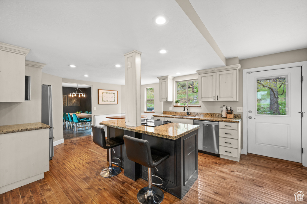 Kitchen with hardwood / wood-style flooring, sink, stainless steel dishwasher, and light stone counters